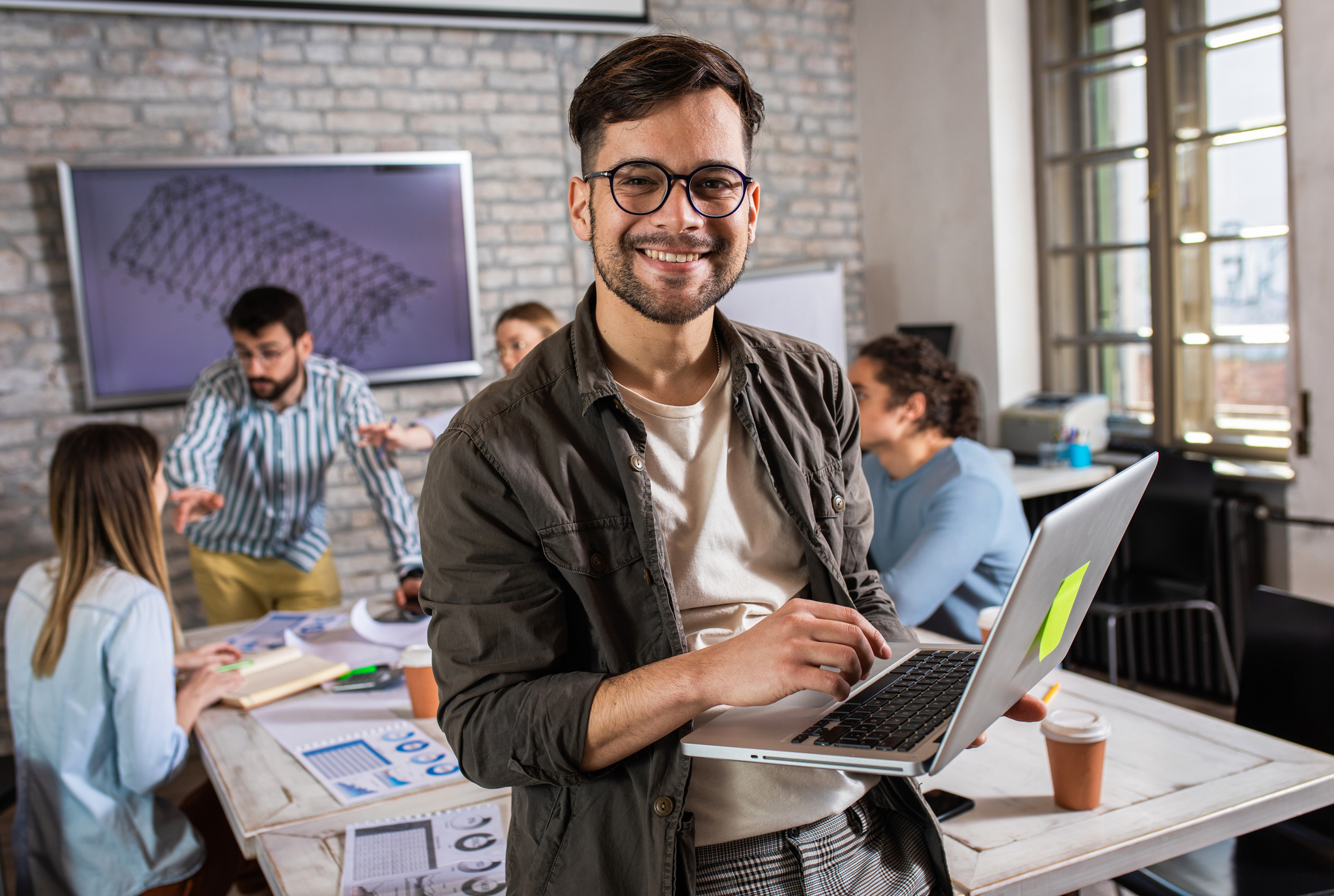 Man smiling while holding a computer.
