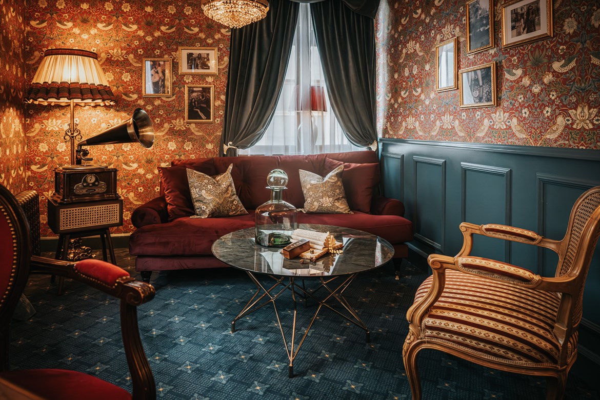 Interiørbilde av salongmøblement på et rom på Charmante Skostredet Hôtel i Bergen. Interiøret er stemningsfull og elegant, og inspirert av den franske storhetstiden i Paris tidlig på 1900-tallet.