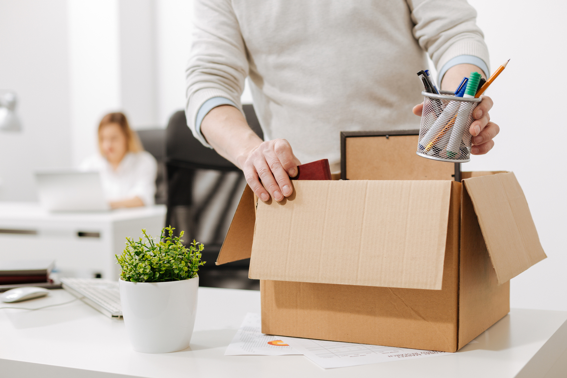 Illustration of the dismissal. A dismissed person packs his things in a box at the office